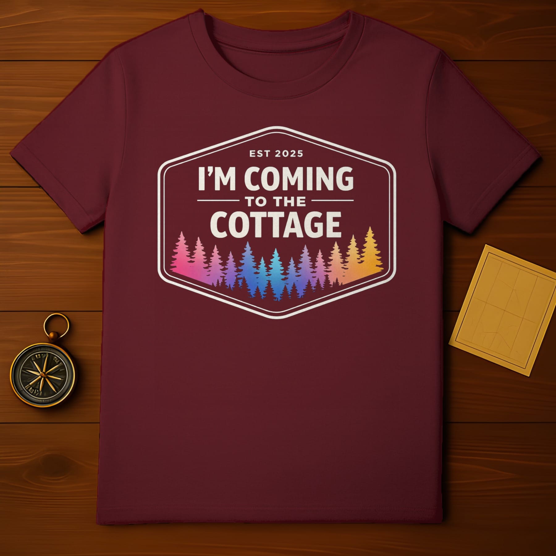 Maroon t-shirt with "I'm Coming to the Cottage Est 2025" in a colorful forest design.