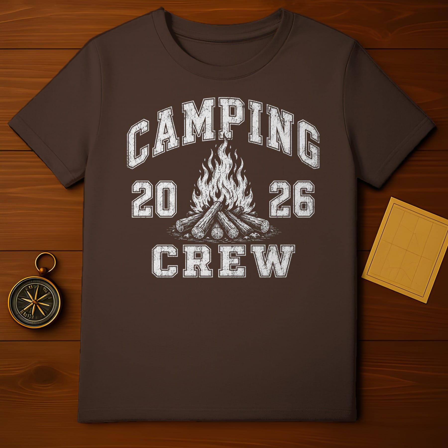 Brown t-shirt with distressed "Camping 20 26 Crew" text and campfire graphic.