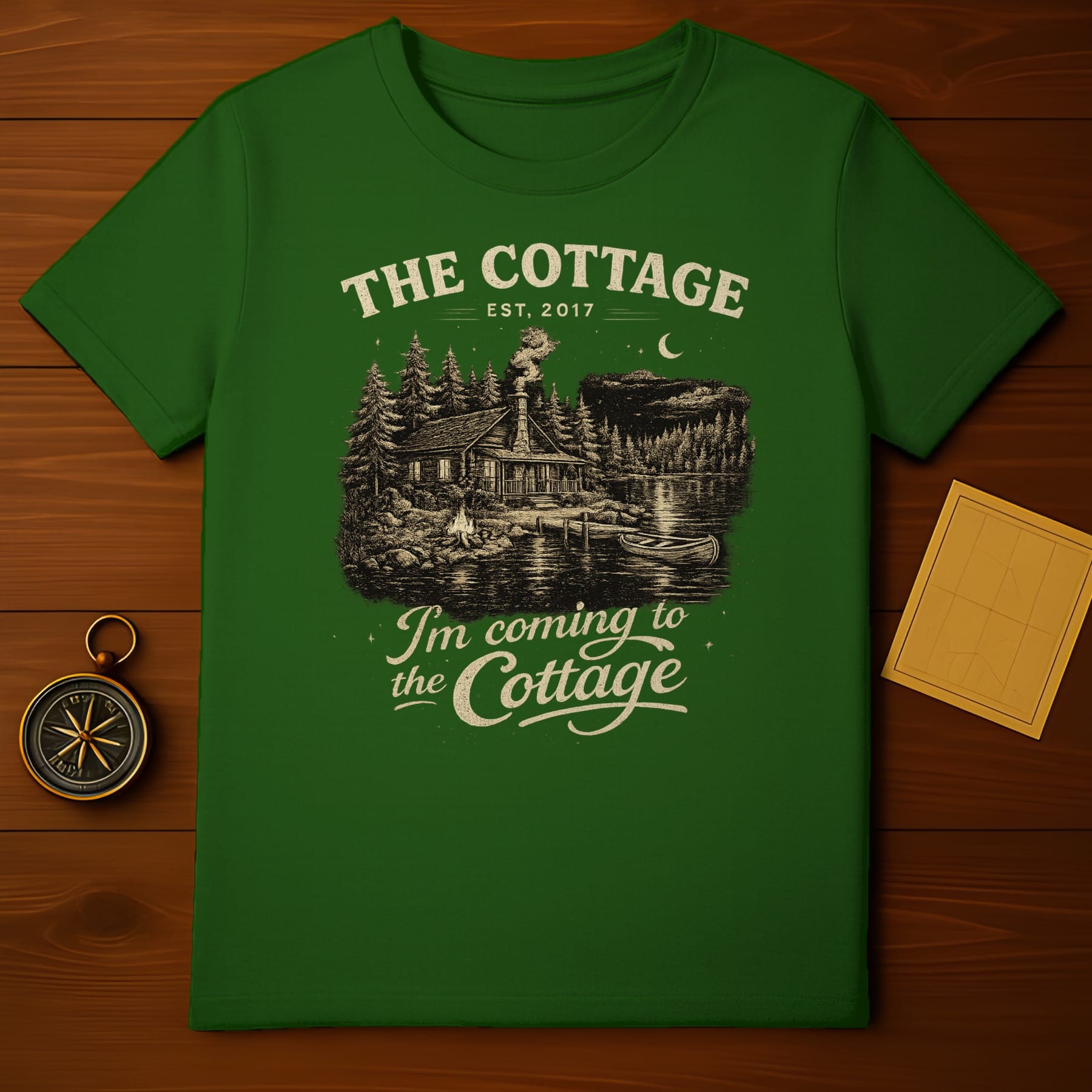 Green t-shirt with "The Cottage" text and woodland scene.
