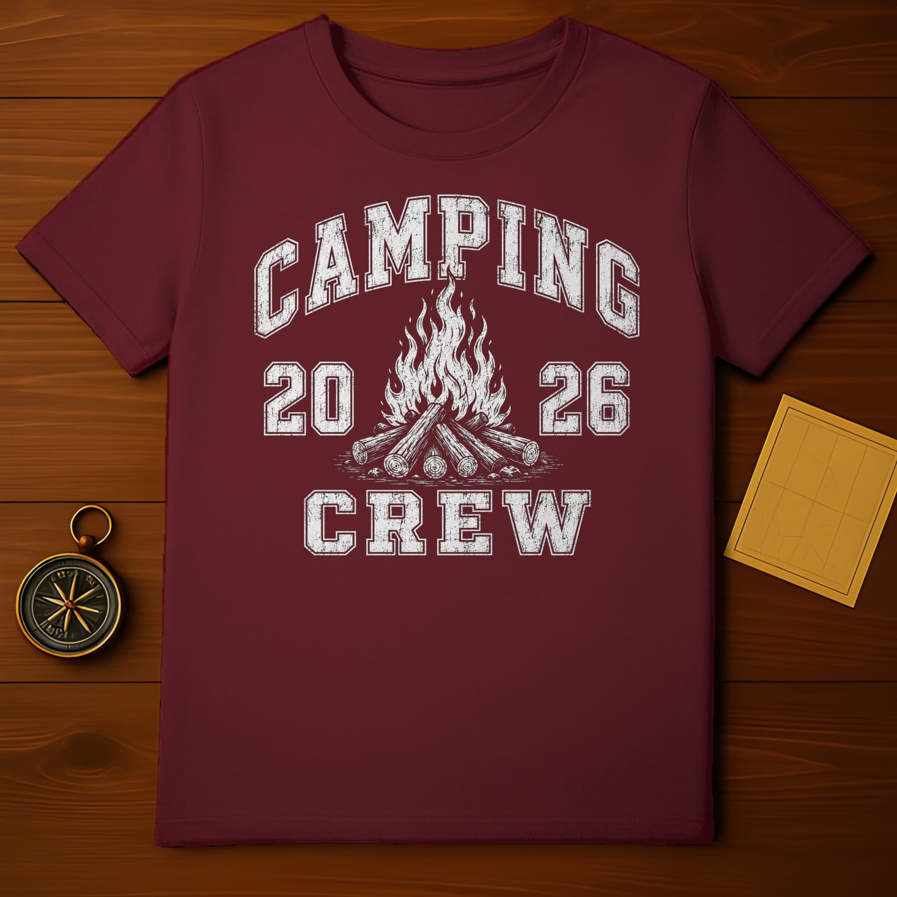 Maroon t-shirt with distressed white text "CAMPING 20 26 CREW" and campfire graphic.