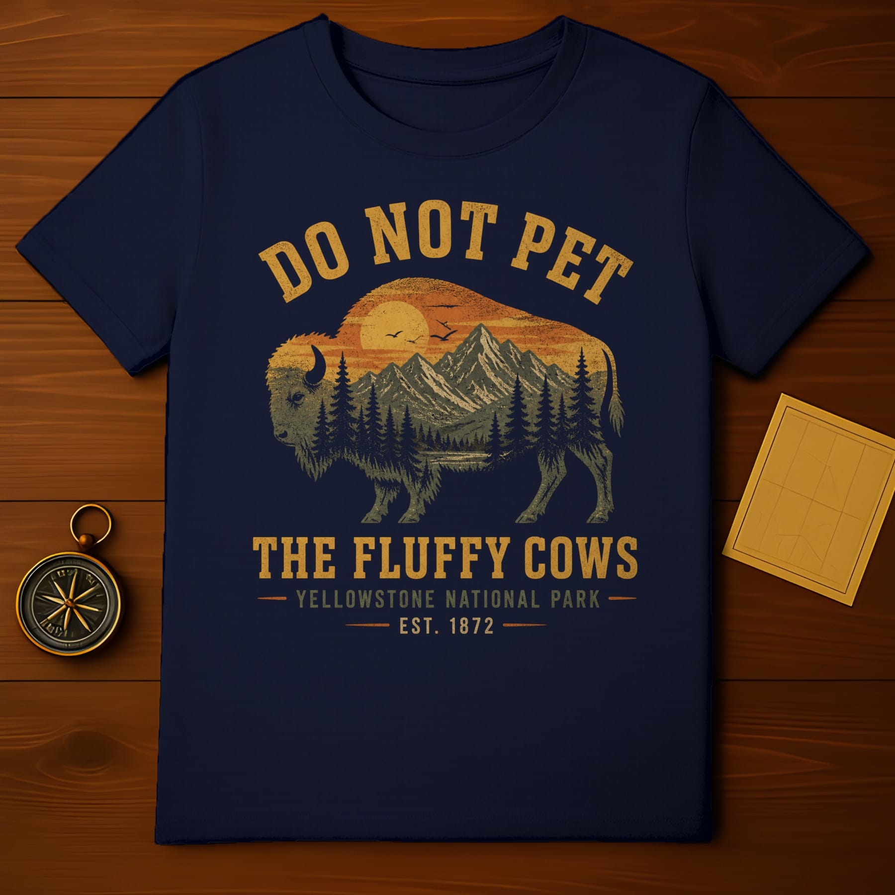 Navy t-shirt with a graphic of a bison, mountains, and sunset, "Do Not Pet The Fluffy Cows Yellowstone National Park" text.