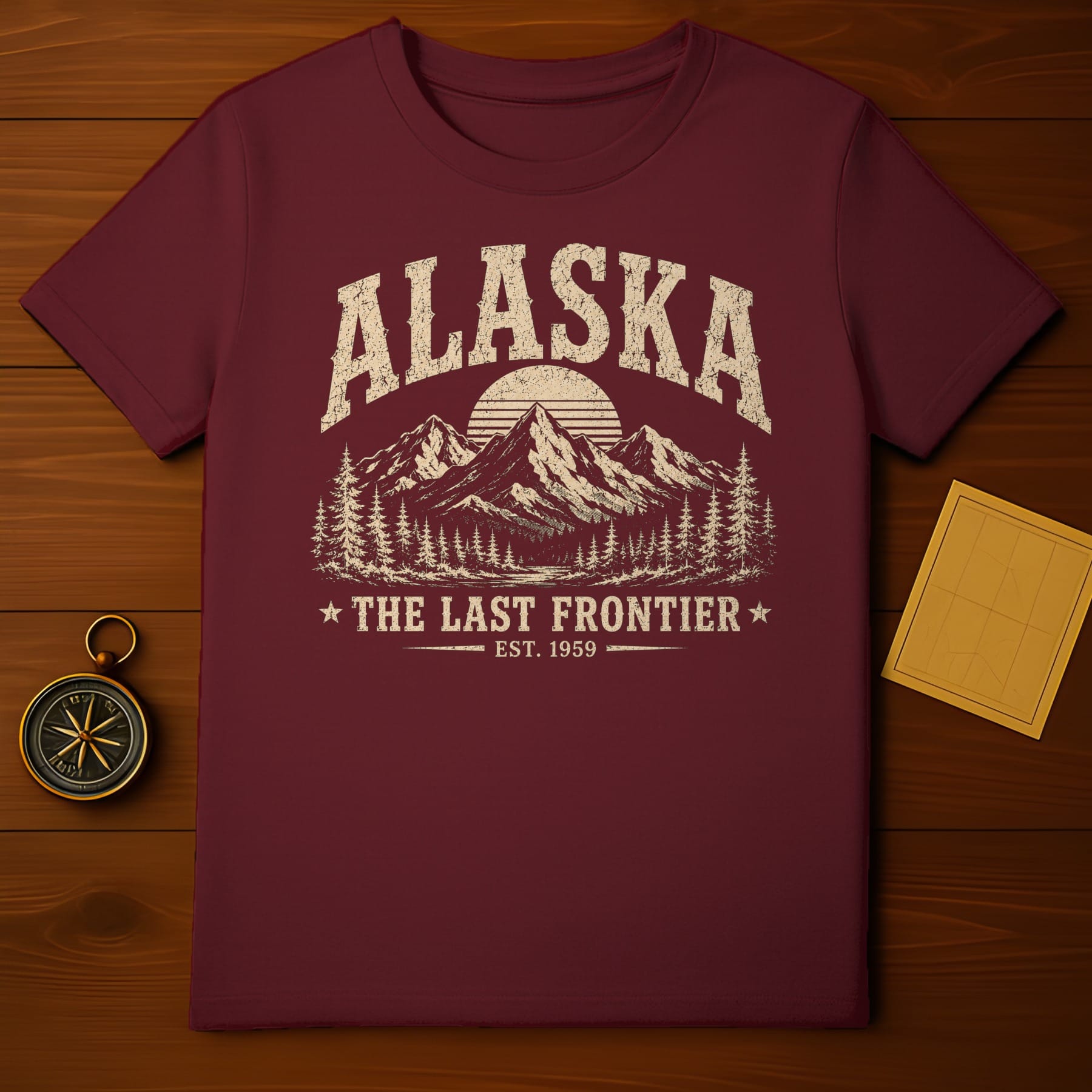 Maroon t-shirt with distressed Alaska mountain graphic and "The Last Frontier Est. 1959" text.