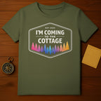 Olive green t-shirt with "I'm Coming to the Cottage Est 2025" and colorful forest design.