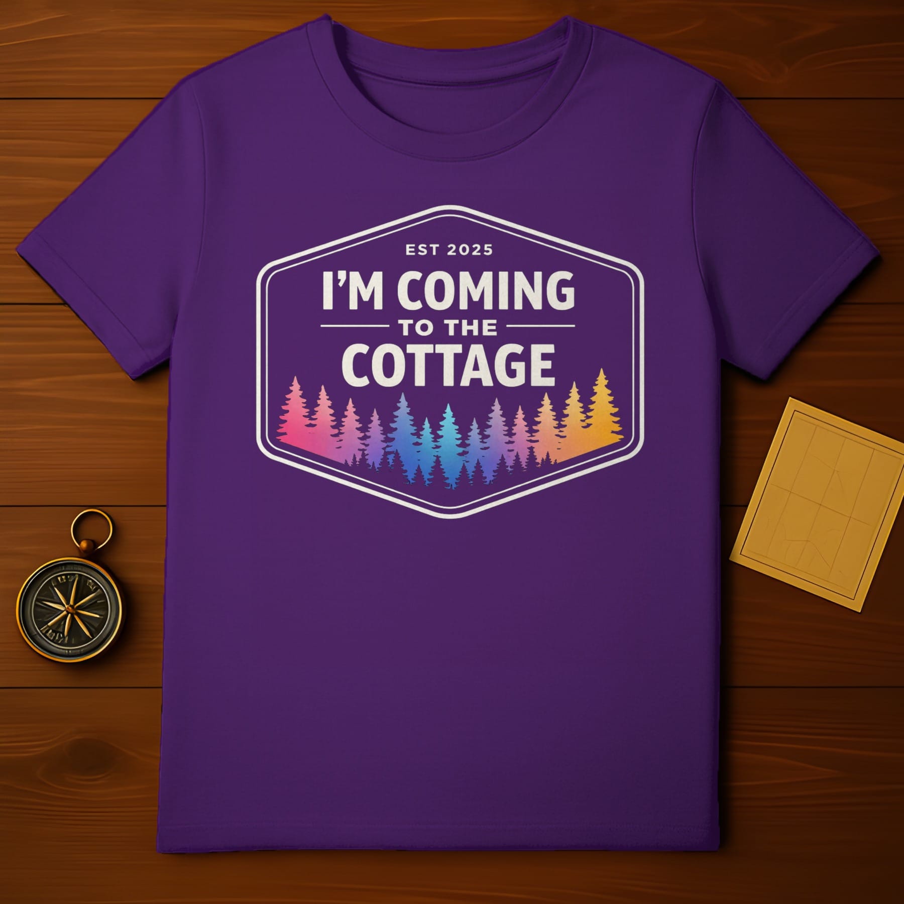 Purple t-shirt with "I'm Coming to the Cottage" in a badge with colorful trees.