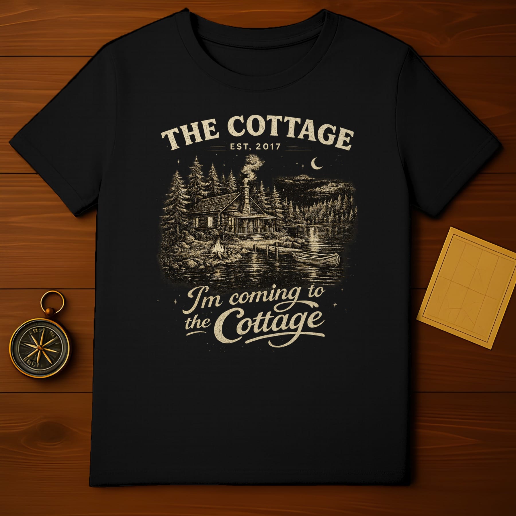 Black t-shirt with "The Cottage Est. 2017" and cabin scene.
