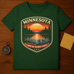Green t-shirt featuring a sunset over a lake with two ducks, forest, and "Minnesota Land of 10,000 Lakes" text.