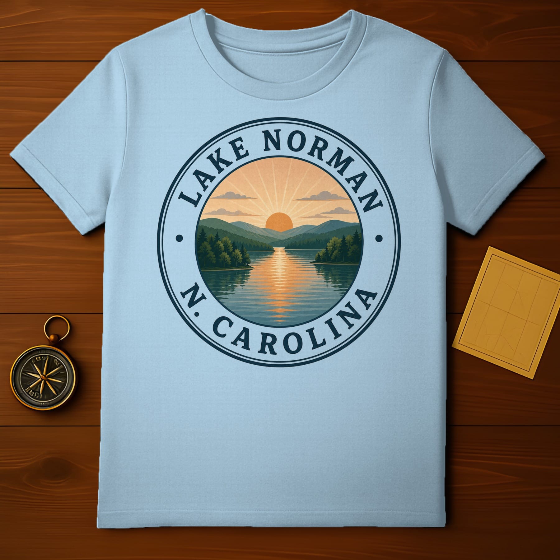 Light blue t-shirt with Lake Norman, N.C. circular graphic featuring a sunset over water.