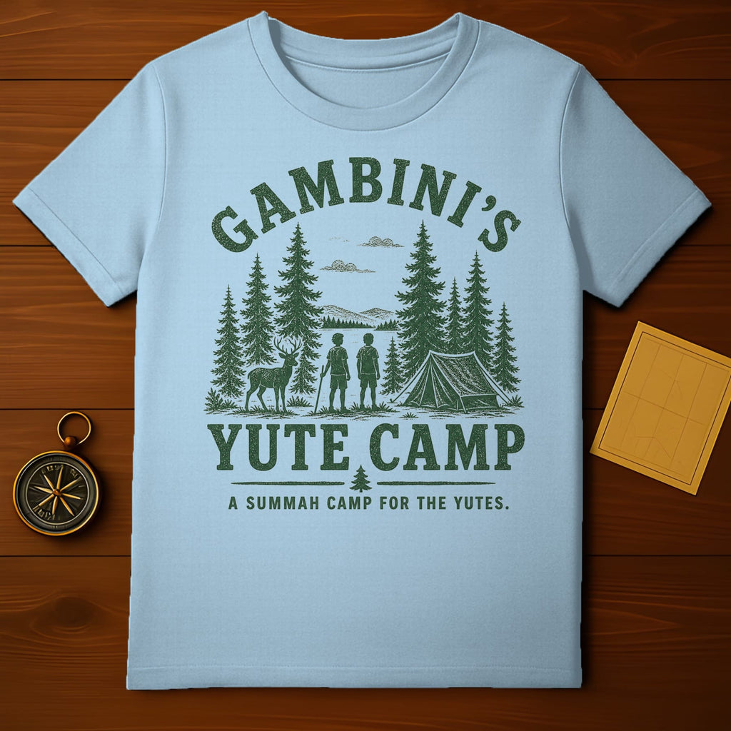 Light blue t-shirt with "Gambini's Yute Camp" text and forest scene.
