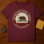 Maroon t-shirt featuring a circular emblem with a bear and "John Muir Woods National Monument California Republic".