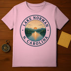 Pink t-shirt featuring a circular graphic of Lake Norman, North Carolina with sunset over mountains.