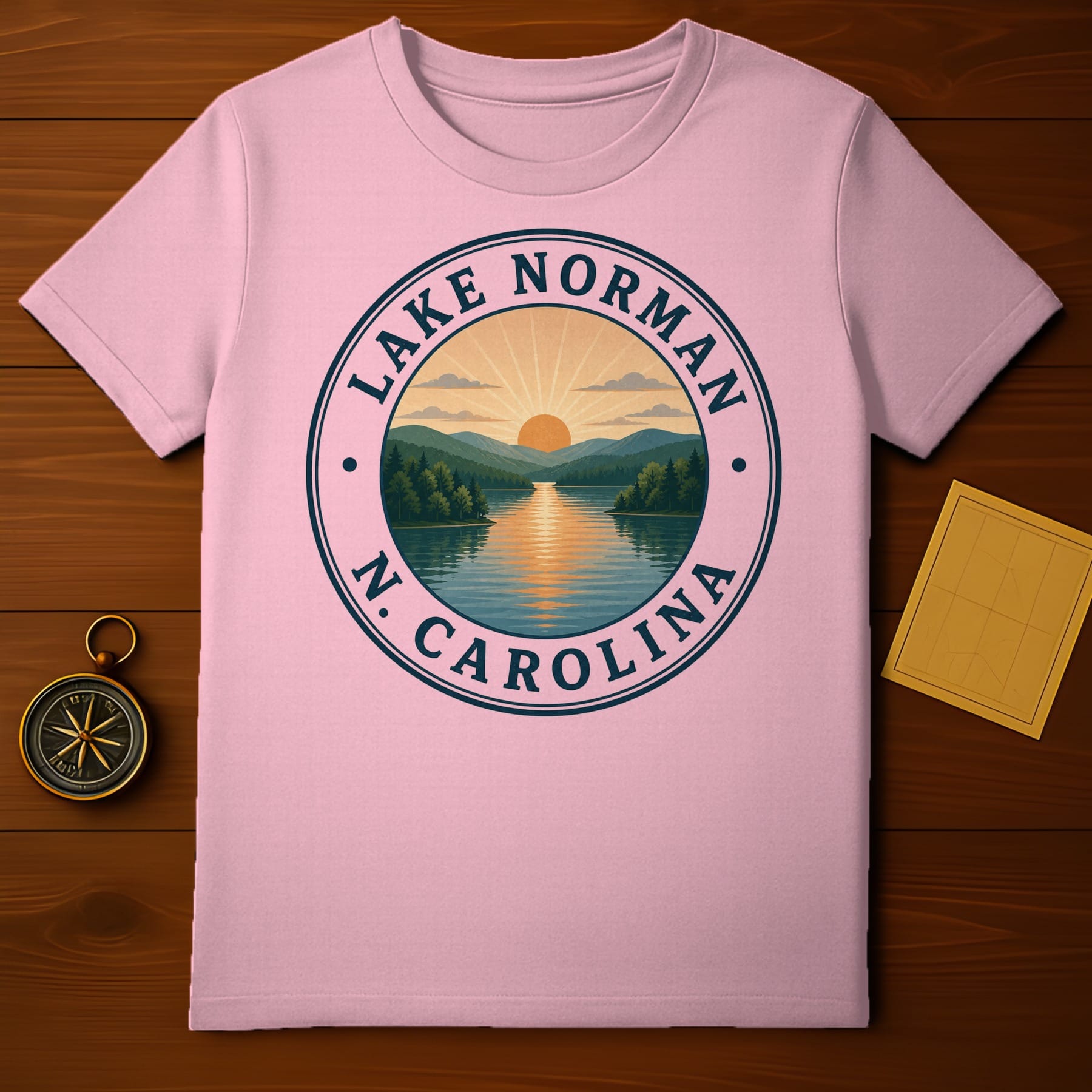 Pink t-shirt featuring a circular graphic of Lake Norman, North Carolina with sunset over mountains.